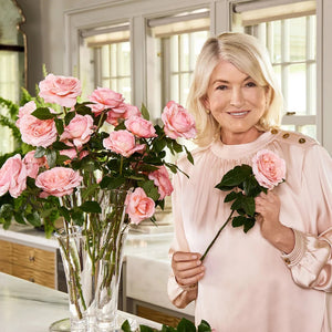 Martha Stewart holding pink roses in her kitchen